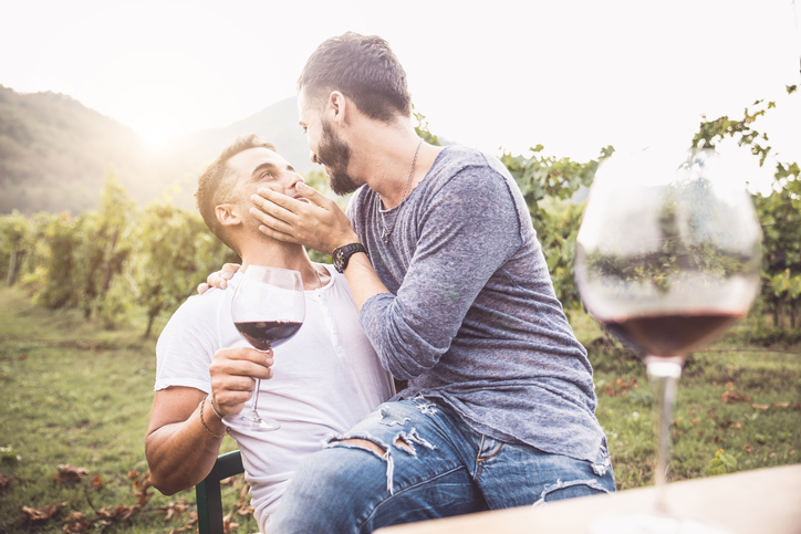 Gay couple at a romantic date, having fun and drinking wine - Homosexual pair kissing
